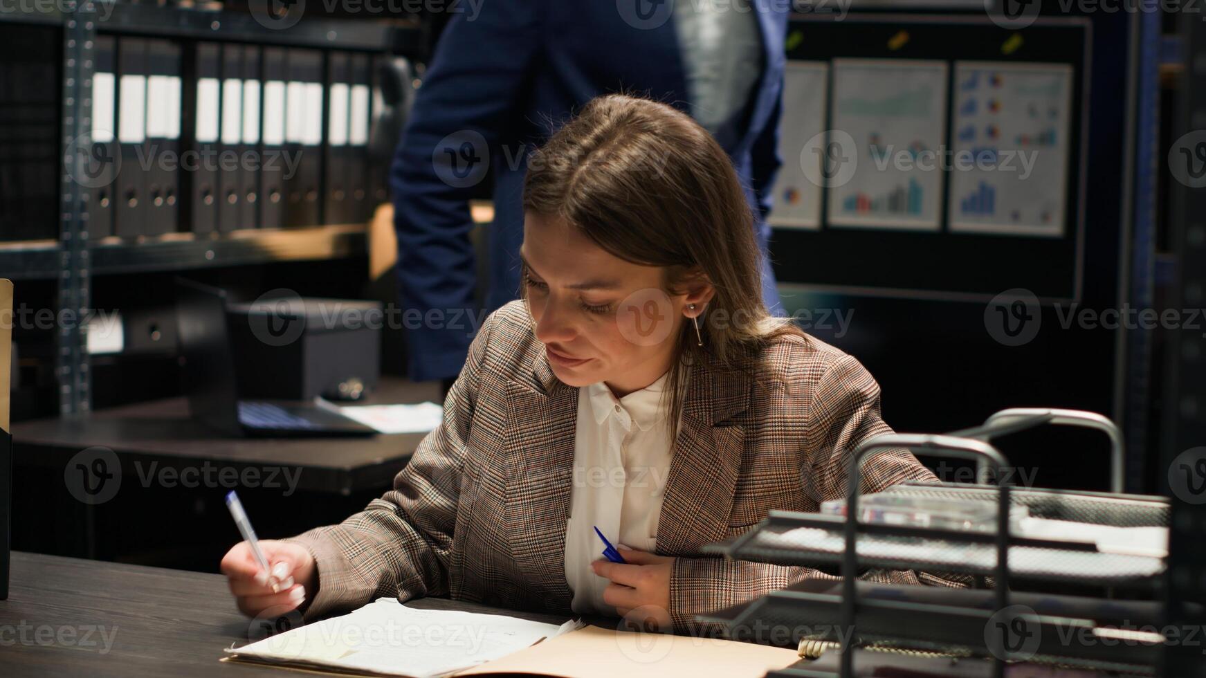 Female law officer receives crucial information on landline and shares new case clues with african american detective. Caucasian investigator answering call on telephone in incident room. Tripod shot. photo