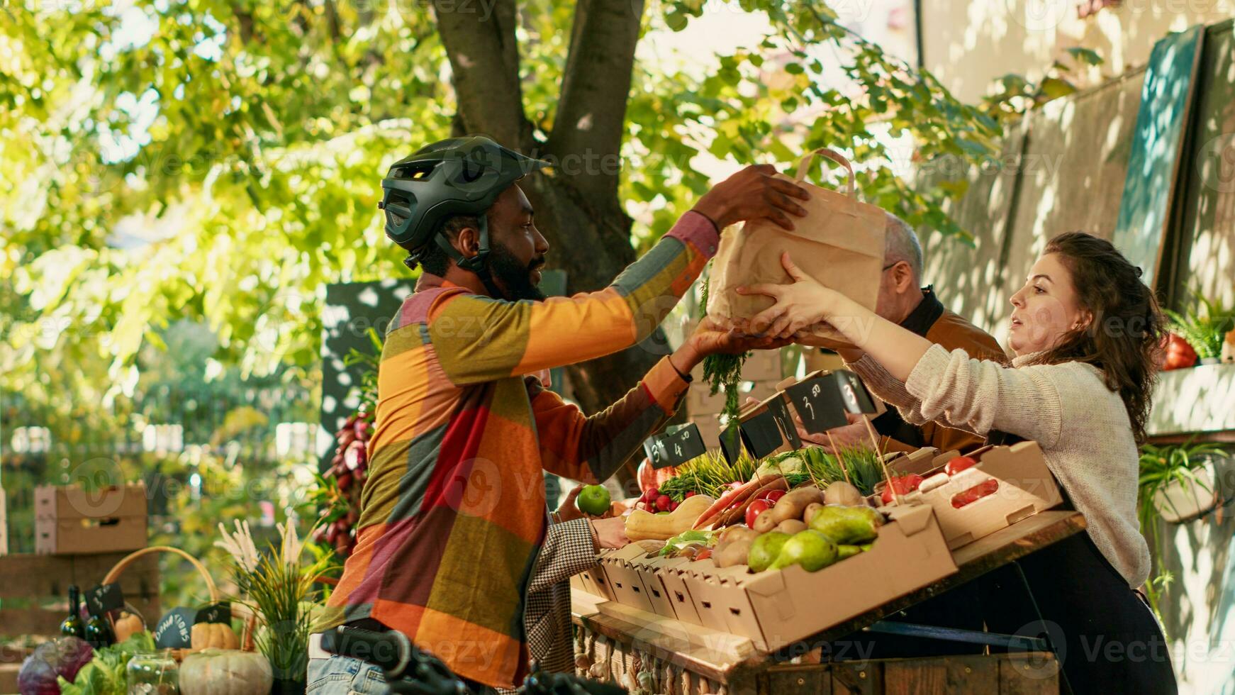 Female vendor giving frutis and veggies order to deliveryman, picking up food to deliver to customers. Male courier riding bike and carrying backpack, healthy produce delivery. photo