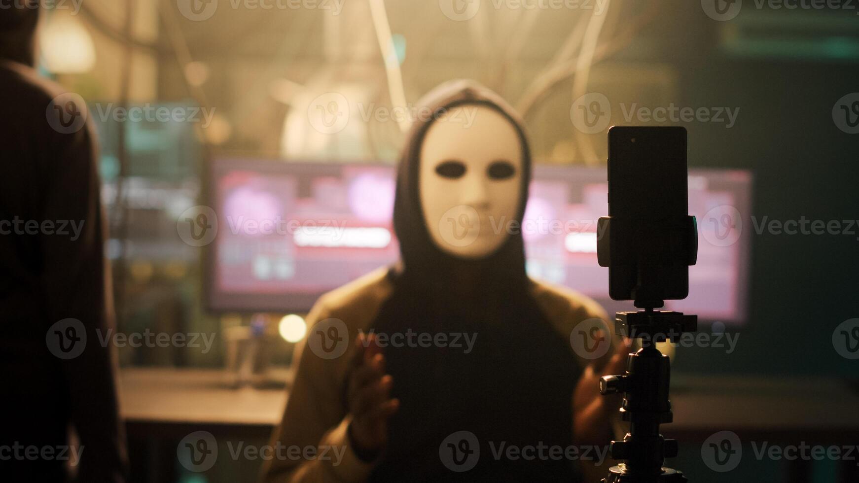 Skilled masked spies using live stream to carry out cyber attacks and ask for ransom to stop ransomware. People recording video on smartphone, dark web network for illegal activities. photo