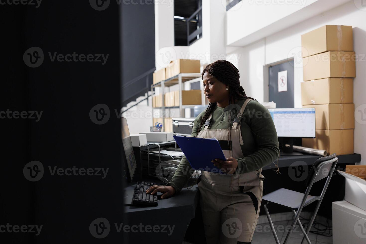 Storage room employee working at goods inventory, analyzing merchandise checklist on computer in storehouse. African american worker preparing customers orders during warehouse inventory photo