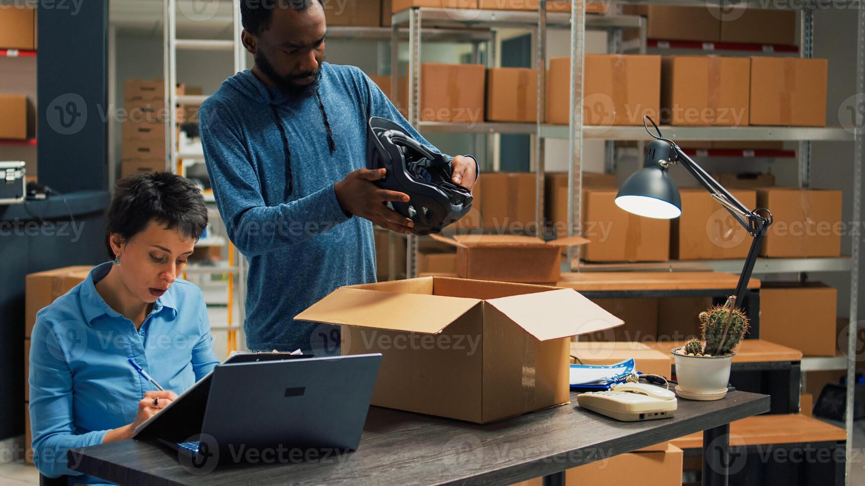 Young entrepreneurs working on goods shipment in warehouse space, putting merchandise from racks in cardboard boxes. Team of partners using products to work on startup development. photo