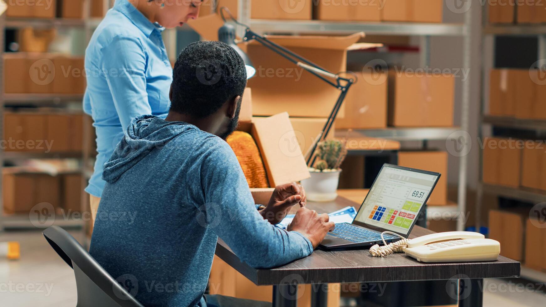 Entrepreneurs doing products quality control for startup development, working on stock shipment with laptop at warehouse space. Team of partners doing teamork to ship merchandise. Tripod shot. photo