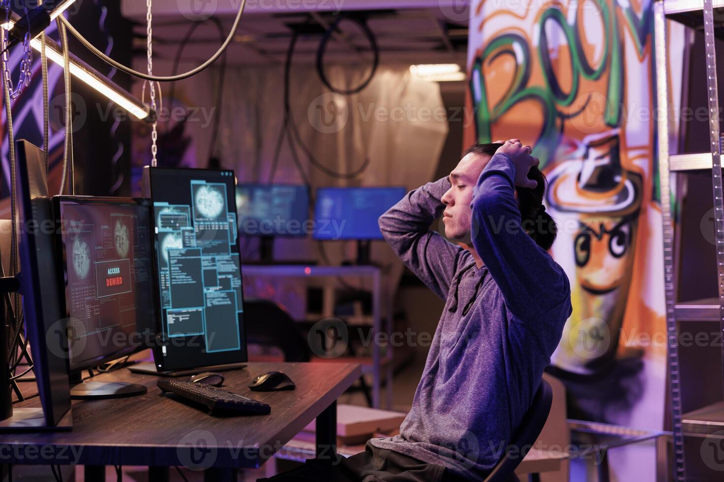 Upset hacker unsuccessfully hacking server while breaking law and doing illegal activity. Disappointed criminal holding head while getting access denied message on computer screen photo