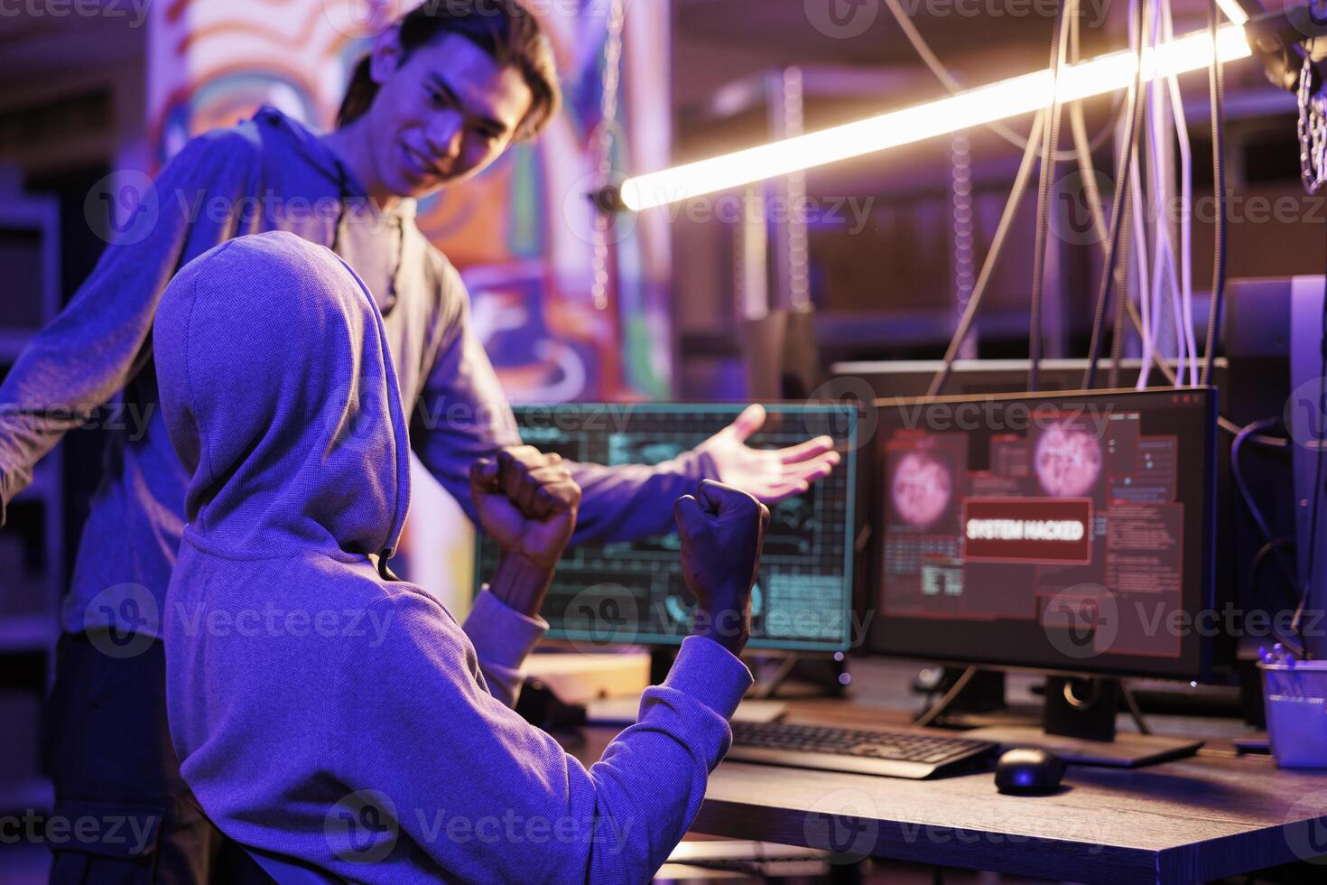 Smiling criminals hacking database and showing victory gesture after successful breach. Happy young hackers celebrating breaking into website and passing cybersecurity system photo