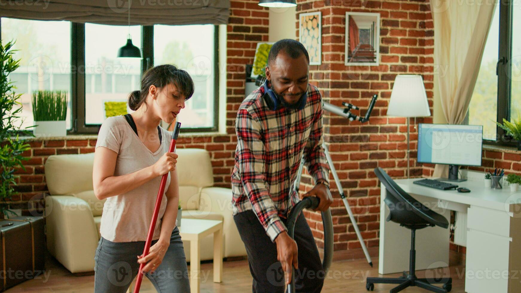 diverso vida socios bailando y barriendo polvo apagado pisos, utilizando vacío limpiador y Lavado solución. alegre Pareja riendo y disfrutando primavera limpieza en departamento, casa quehaceres. foto