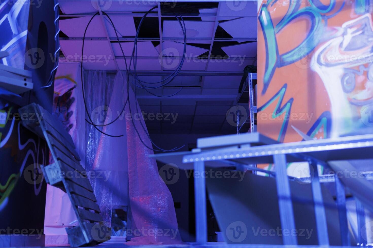 Destroyed old space with bright lights turned into ruin, deserted urban ghetto glowing in the darkness of disintegration. Neglected abandoned place with fluorescent purple light. photo