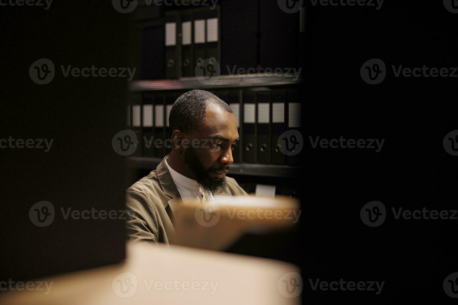 Private detective searching information in police records and working late. Policeman sitting in room with racks full of folders with case files and solving crime at night time photo