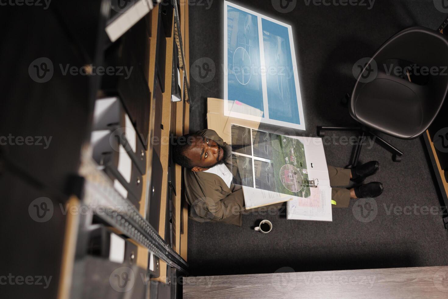 African american man examining augmented reality clues, checking evidence and case files in private investigation space. Male detective trying to solve crime with artificial intelligence hologram. photo