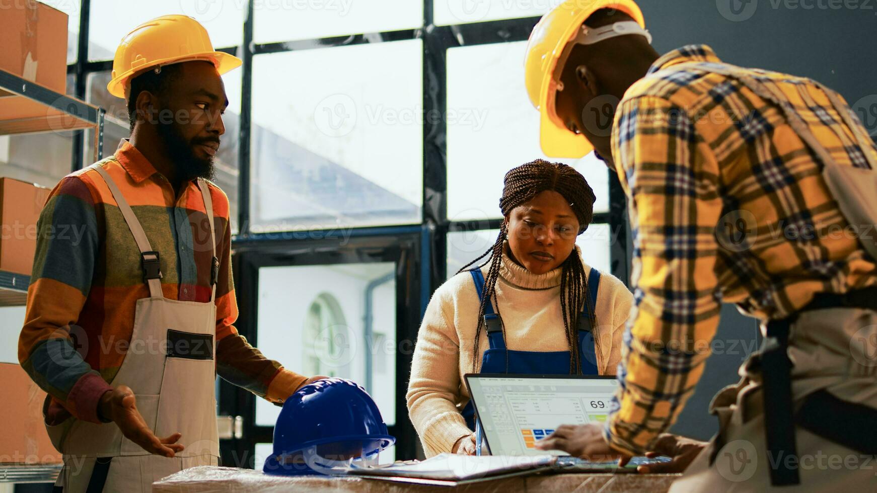 African american people talking about merchandise and retail store distribution, packing cardboard boxes with tools in warehouse. Cheerful storage room employees working on industry production. photo