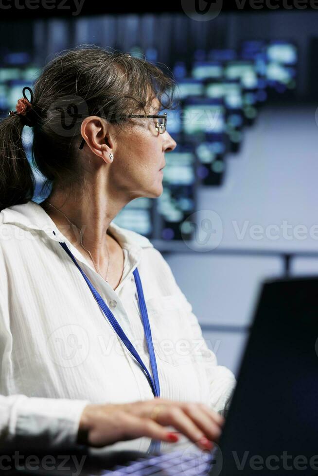 Senescent manager preparing server clusters contingency plan, monitoring data center energy consumption across components, making sure sensors are functioning faultlessly, doing routine disk checks photo