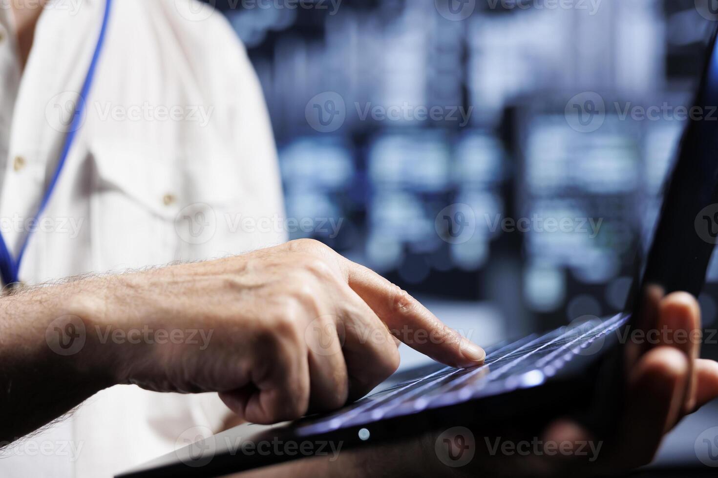 Overseeing manager using laptop to examine blade servers for power fluctuations, close up. Experienced supervisor monitoring high tech data center systems, identifying potential malfunctions photo