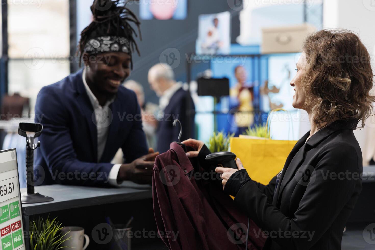Elegant customer talking with manager at cash register, making transaction on pos terminal in shopping center. Boutique employee scanning shirt using store scanner, commercial activity. photo