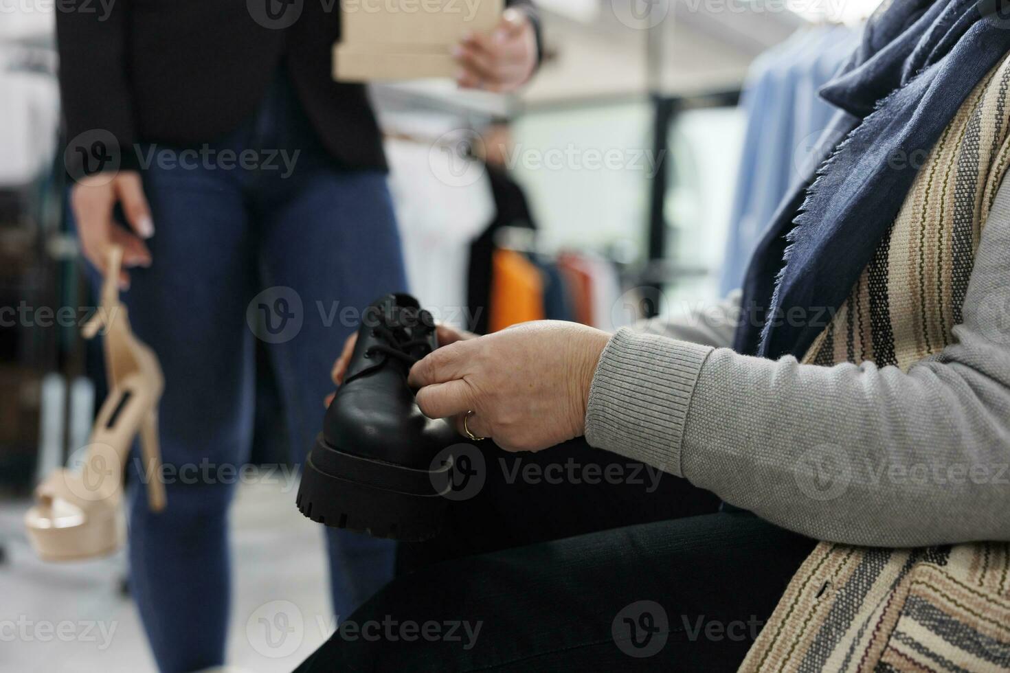 Fashionable shopper trying stylish black shoes, shopping for formal wear in clothing store. Elderly woman buying elegant clothes and merchandise in boutique, commercial activity. Close up photo
