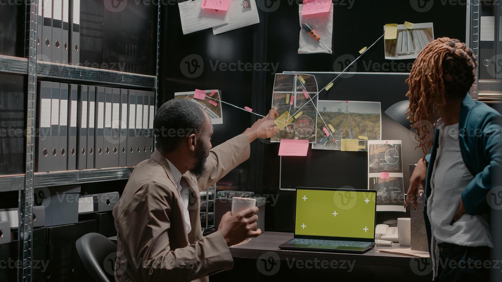 Two inspectors using greenscreen on laptop at desk, analyzing case reports in police archive files. Private detectives team looking at isolated display with blank copyspace on screen. photo