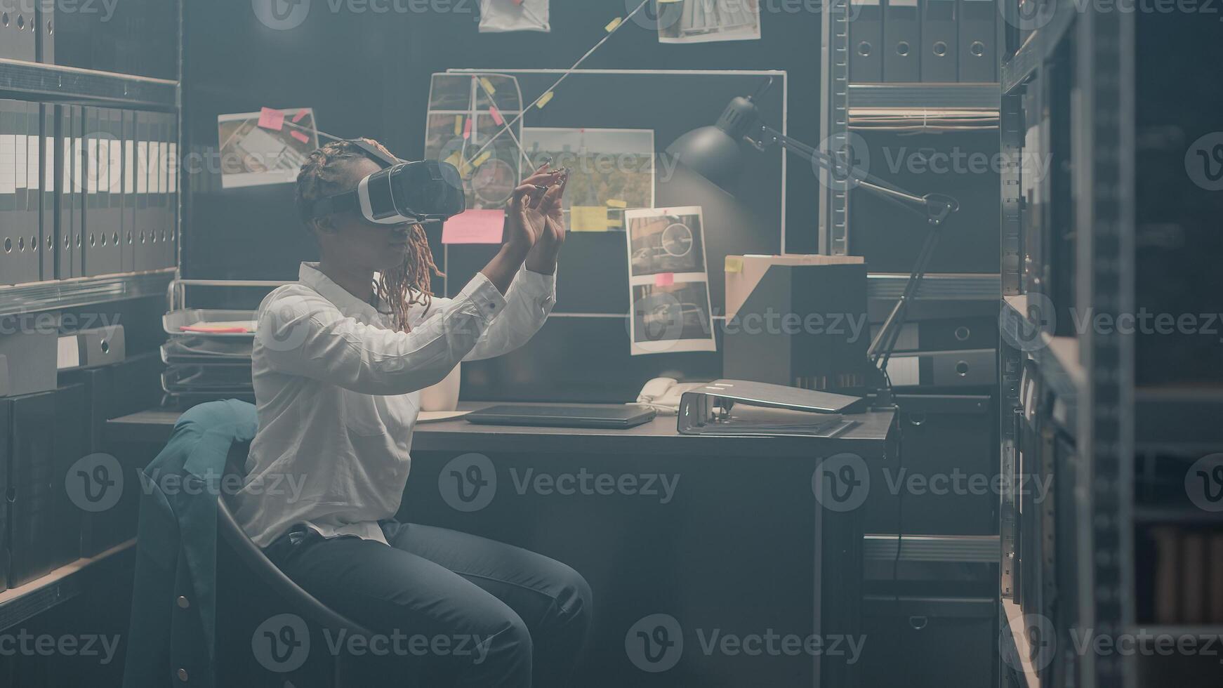 Private detective working with 3d vr glasses in police archive, using interactive virtual reality headset to solve crime. Security agent checking evidence reviewing surveillance photos. Tripod shot. photo