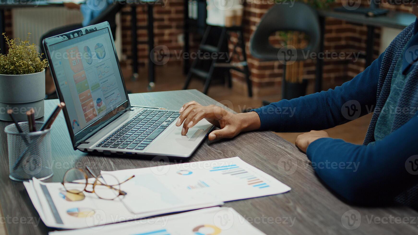 Young businessman working with laptop and reviewing company analytics, trying to increase profit with annual statistics. Employee in startup office planning corporate development, data reports. photo