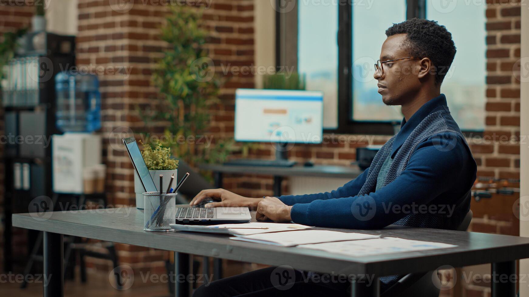 Young employee using laptop at desk, reading official reports information to help increase profit. Company analyst reviewing data statistics to build new business vision for development. photo