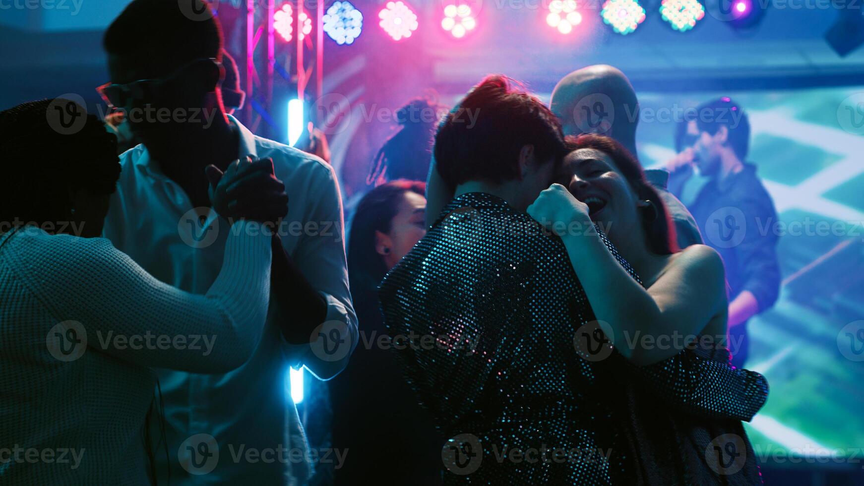 Dance partners waltzing on dance floor, attending party with friends at discotheque. Young people dancing in pairs on slow romantic music, showing off dance moves at club. Tripod shot. photo