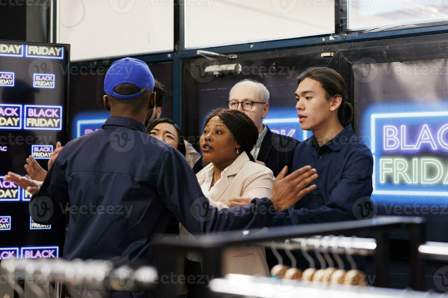 Agressive diverse people shoppers arguing with security guy at clothing shop entrance, waiting in line for Black Friday deals on Thanksgiving. Bargan hunters racing to store in search of holiday deals photo