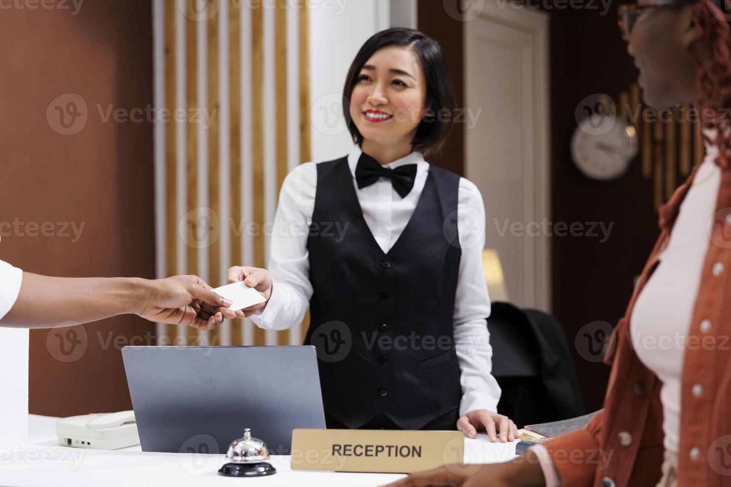Hotel staff giving access room key card to guests after doing check in process, helping with accommodation in lobby. Two people preparing to see room after registering at reception. photo