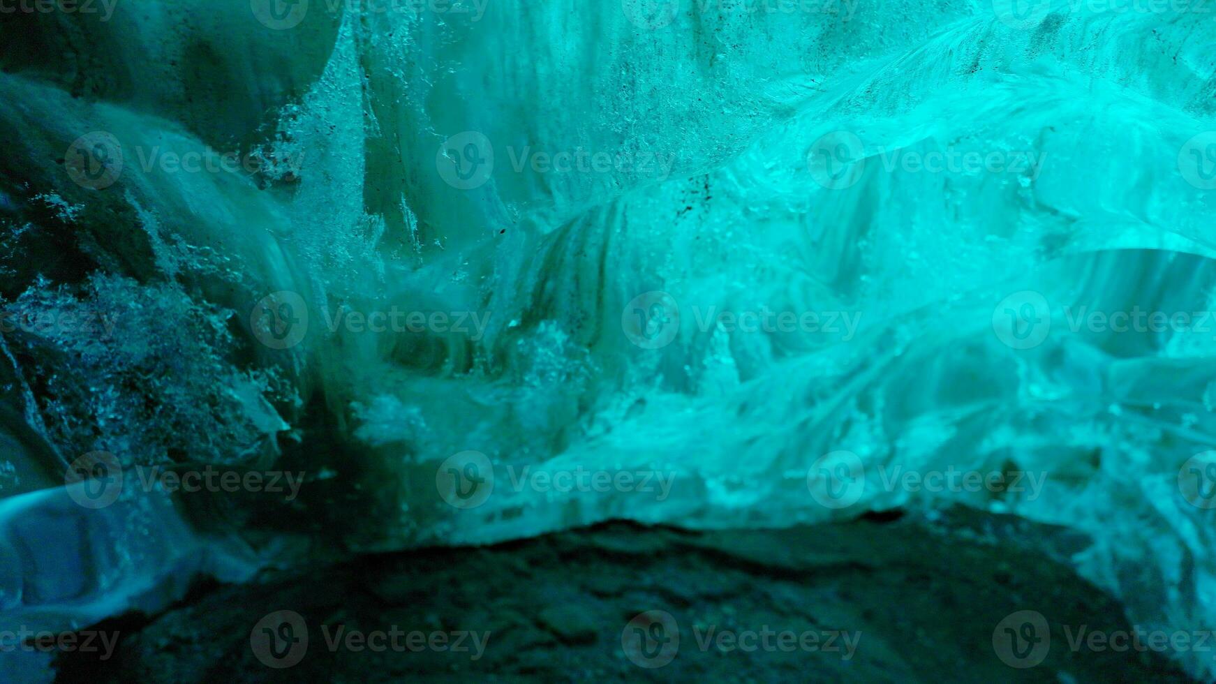 Water dripping from ice rocks in north, global warming concept. Icy blocks melting inside vatnajokull glacier caves, icelandic scenery being destroyed after climate change. Handheld shot. photo