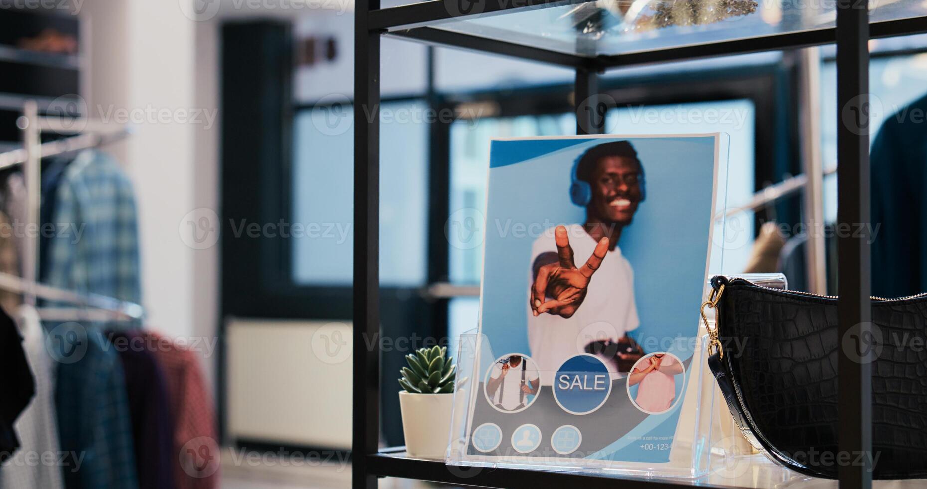 Selective focus of clothing store flyer in empty modern boutique, filled with multiple racks with fashionable merchandise and trendy accessories. Shopping centre equipped with stylish clothes photo