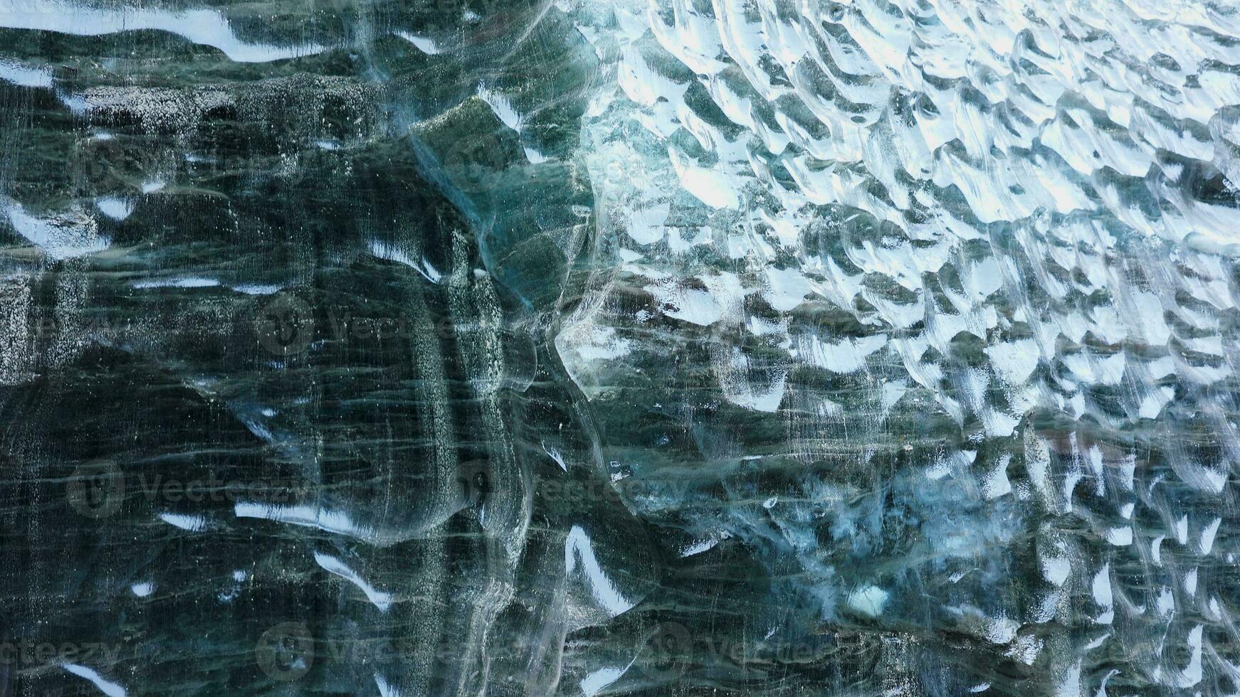 Blue ice mass in vatnajokull crevasse, majestic transparent ice glacier in iceland. Inside ice caves with cracked ice blocks covered in frost rocks, nordic landscapes. Handheld shot. photo