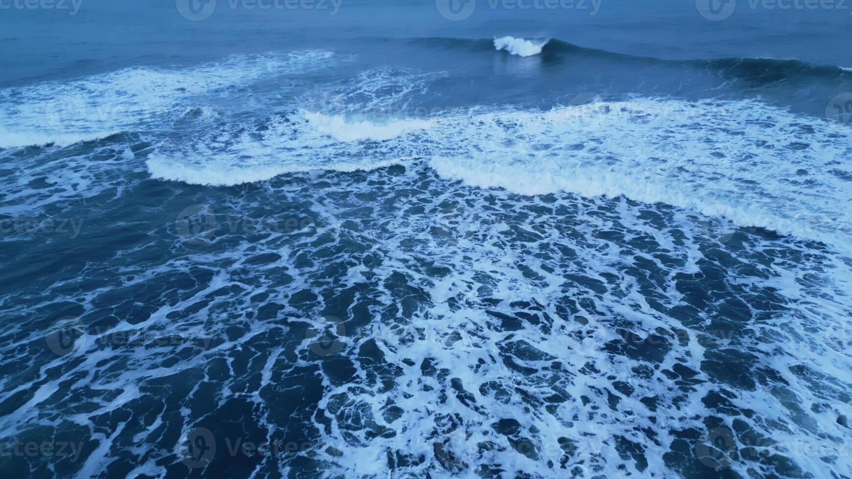 Drone shot of nordic ocean coastline with black sand beaches, icelandic natural scenery. Majestic atlantic shore landscape in iceland with snowy mountains and freezing cold water. Slow motion. photo