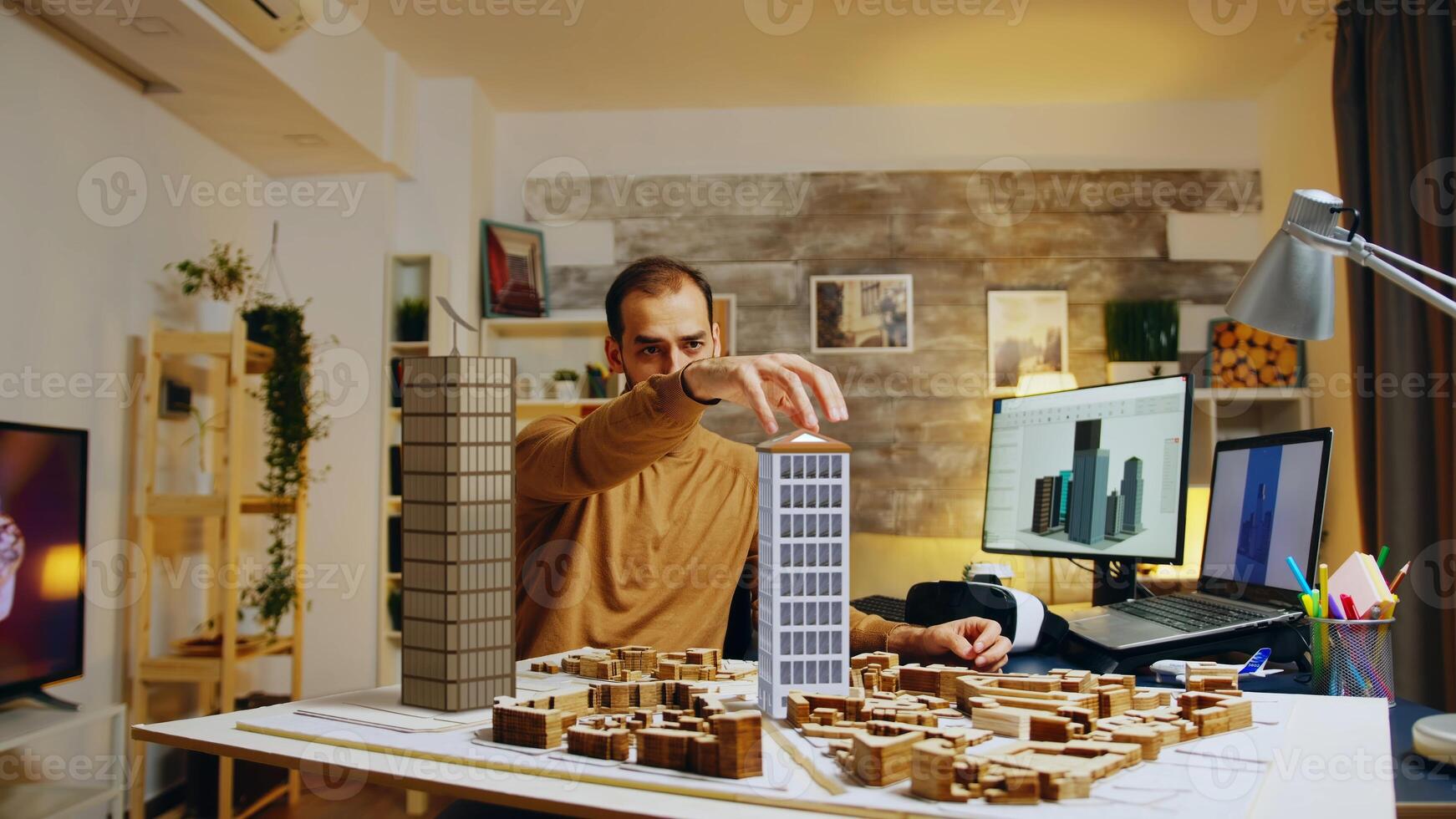 Architect modeling buildings in home office living room, following 3D graphic design sketch plans on computer screen. Professional working on skyscrapper structure maquette photo