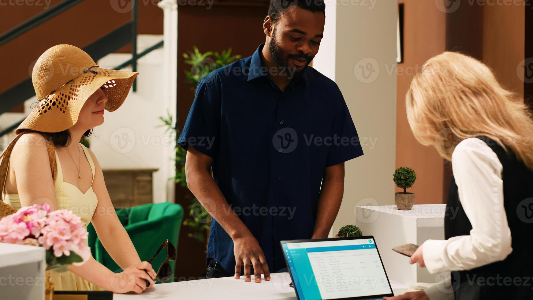 Front desk staff reviewing id papers to register tourists at tropical hotel, looking at identification in reception lobby. Employee doing check in with guests using passports. Handheld shot. photo