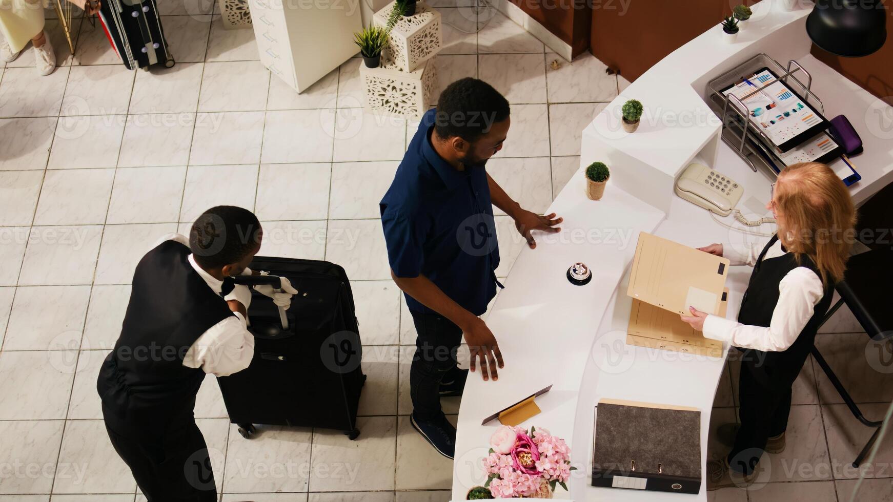 Male tourist arriving at hotel reception, preparing to do check in and start tropical summer vacation. Hotel concierge team providing outstanding service for clients. Handheld shot. photo