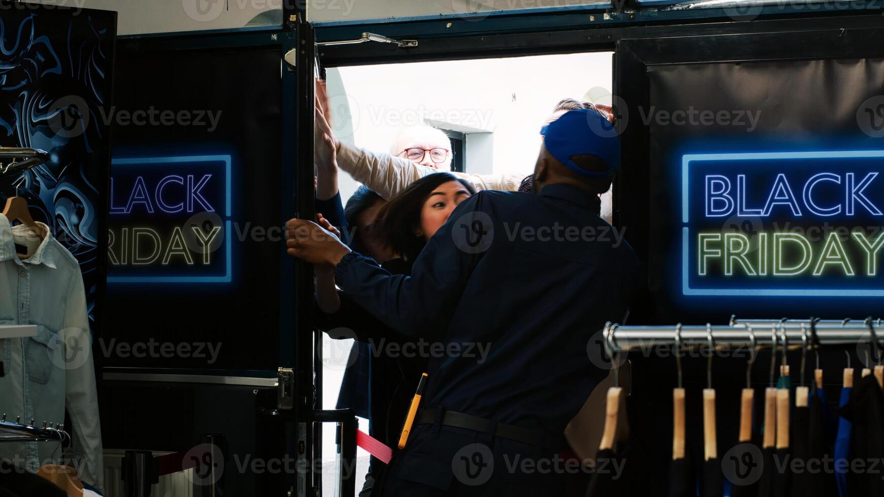 Bargain seeking clients force entering inside clothing store on black friday sales event, angry shoppers. Group of obsessed people pushing door and security guard at shopping center. Handheld shot. photo