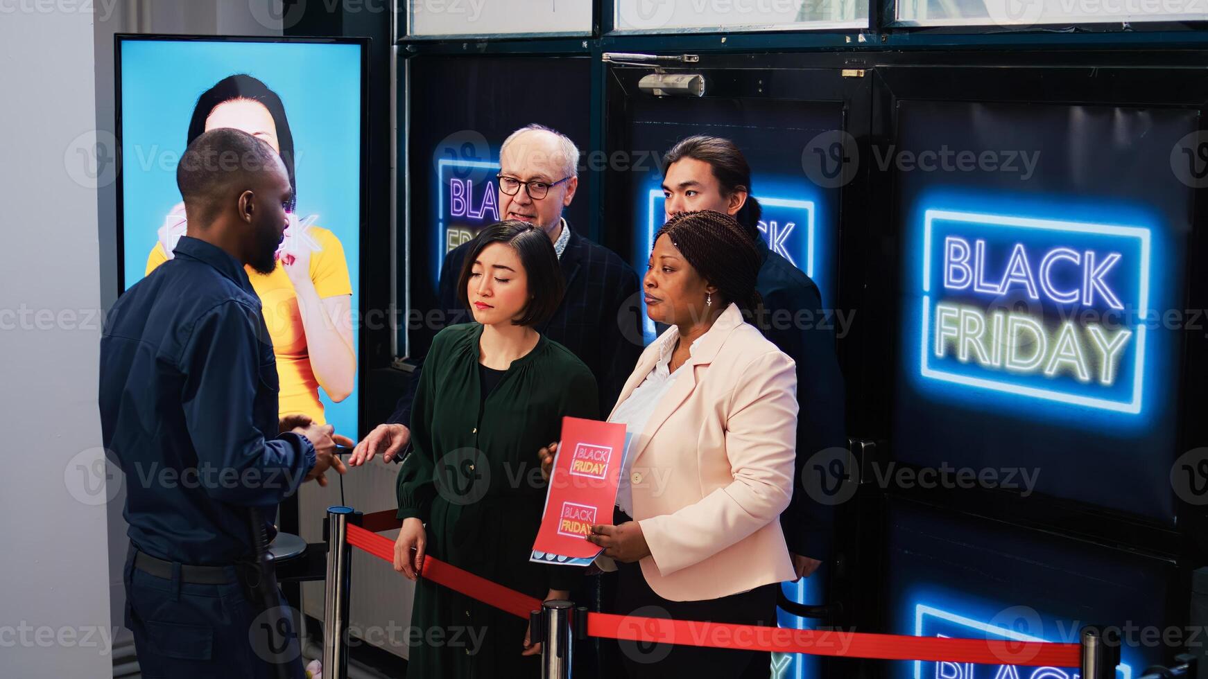 Anxious customers in line for deals on black friday, standing behind red tape at clothing store entrance. Impatient shoppers waiting for opening shop to start promotional shopping spree photo