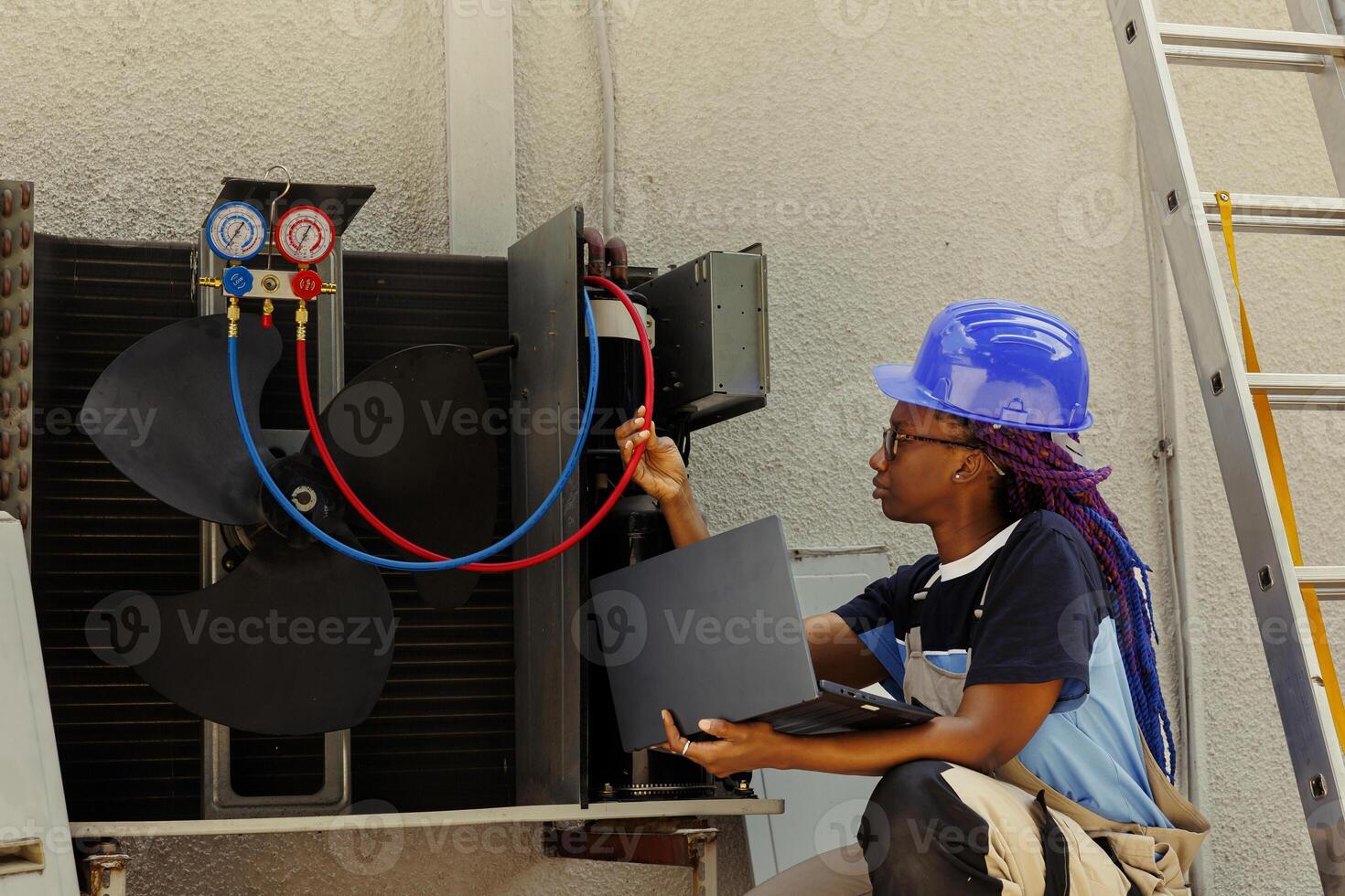 Professional african american worker asked by customer to detect cause of malfunctioning hvac system, keeping track on laptop of nitrogen pressure loss over time using manifold indicators photo