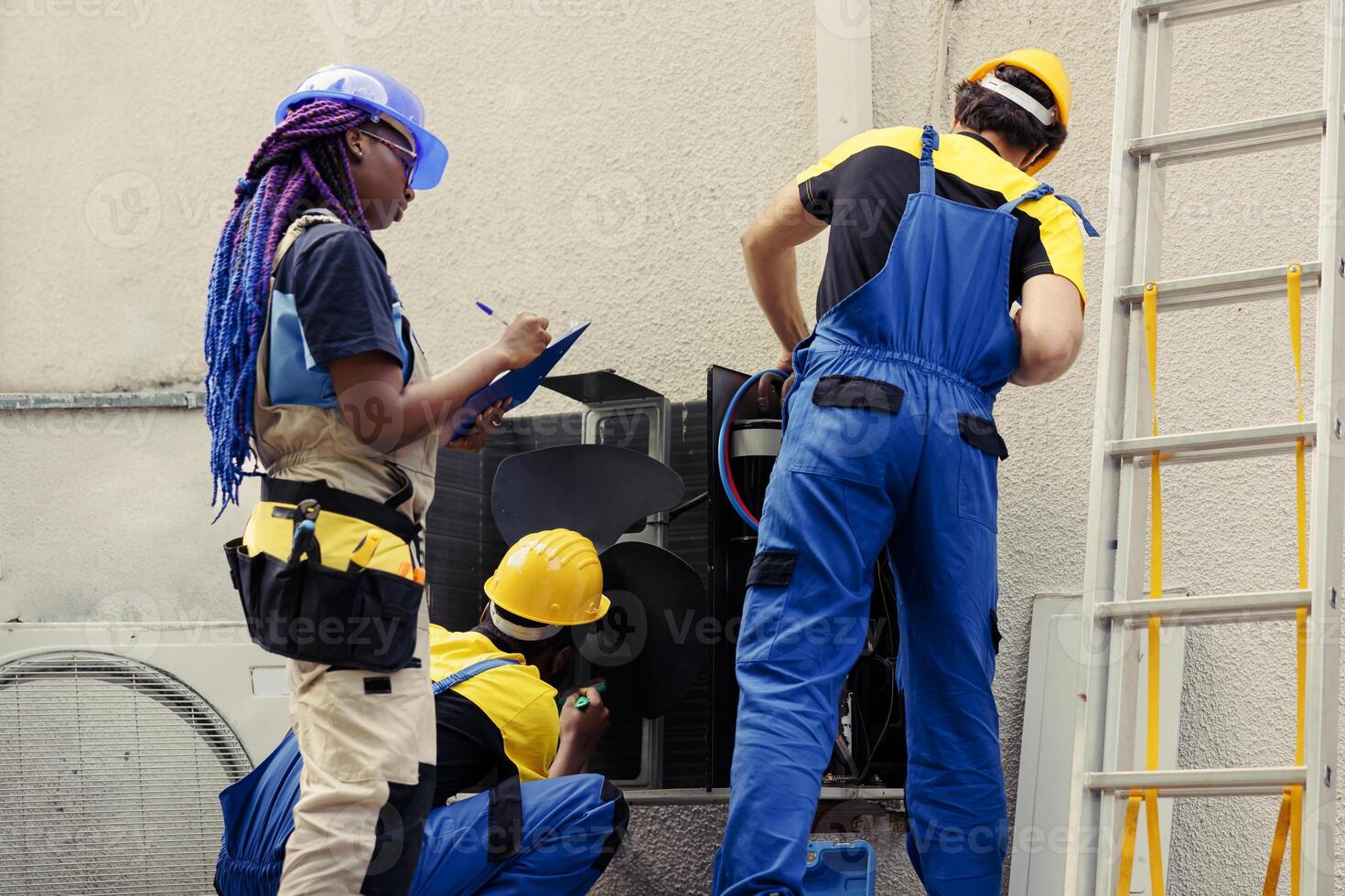 Diverse team of trained engineers working outdoors, checking for clogged air filters restricting condenser airflow, causing cooling system to work harder and consume more energy photo