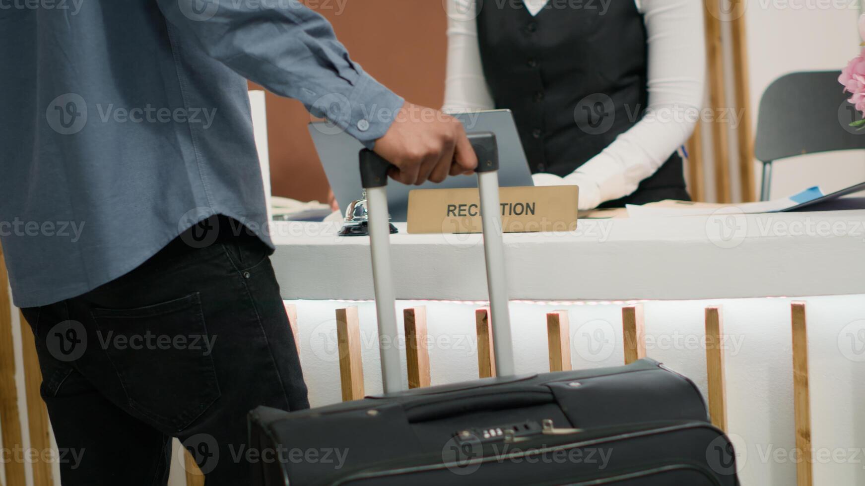 invitado de viaje con carretilla pantalones a hotel, recepción acceso llave tarjeta a recepción después largo vuelo. africano americano turista en vacaciones a cinco estrella fiesta complejo. cerca arriba. Mano disparo. foto