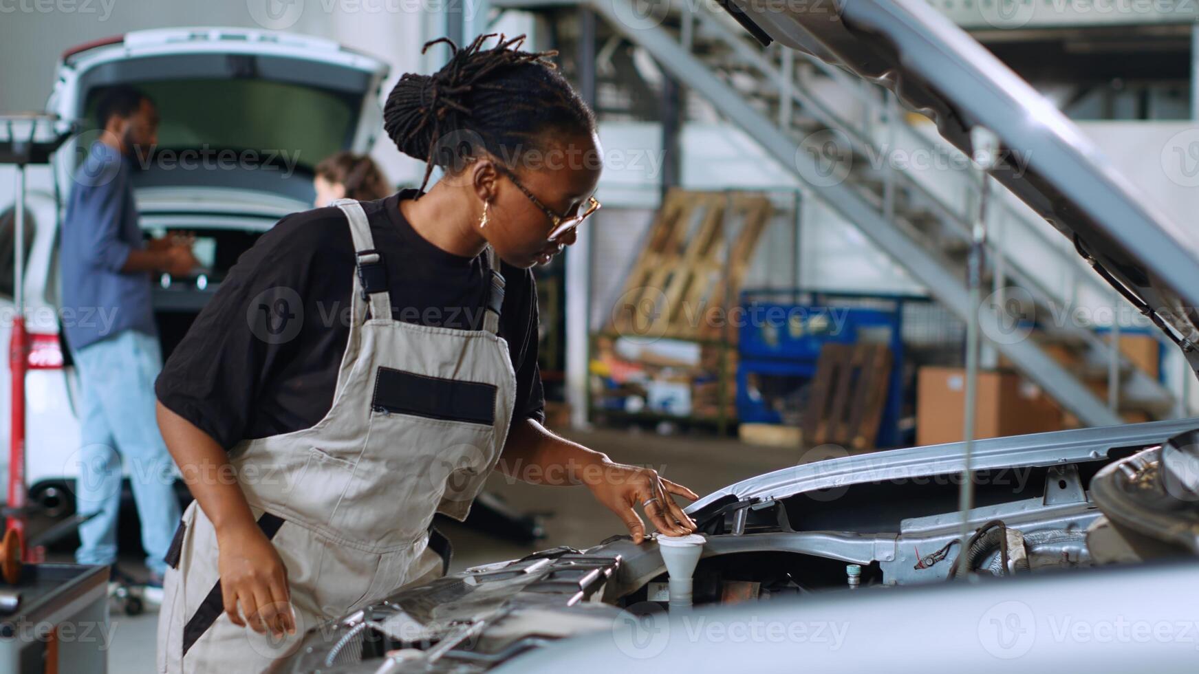 Knowledgeable mechanic in garage using torque wrench to tighten screws inside opened up vehicle, preparing to change oil. Auto repair shop employee doing checkup on car to prevent defects photo
