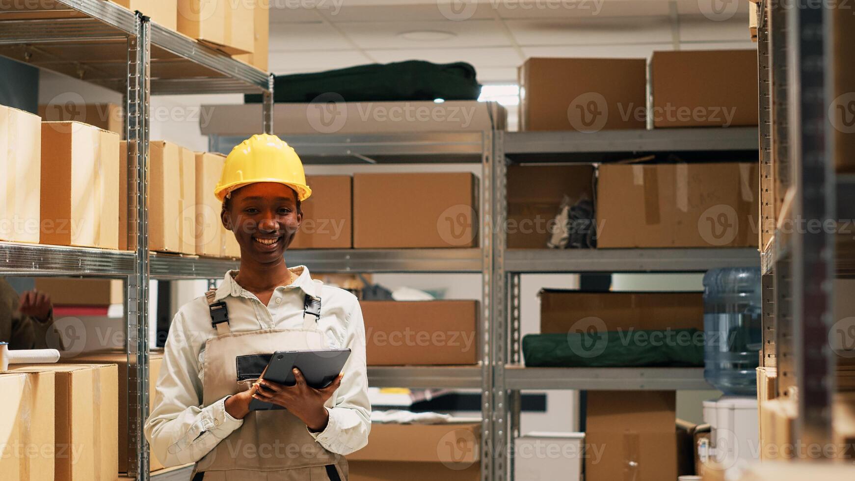 African american woman holding tablet to do inventory in storage room space, using device to check merchandise stock before shipping products. Female worker planning order distribution. photo
