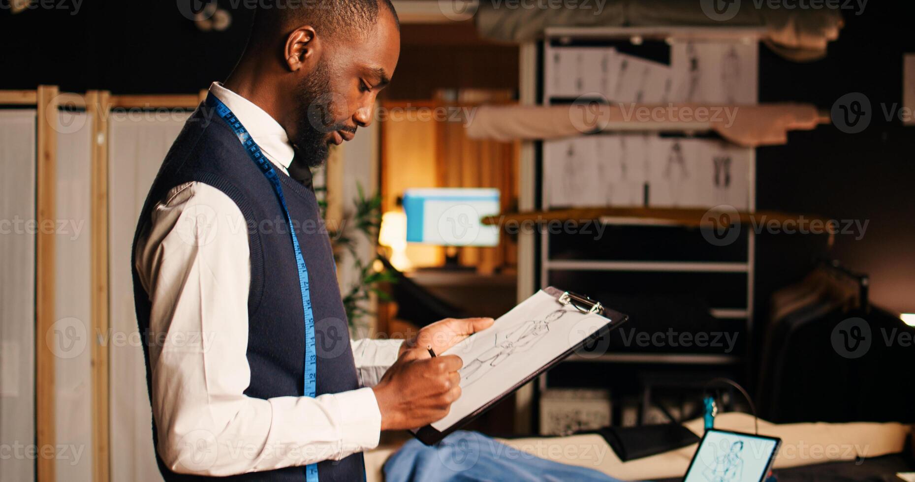 African american tailor drawing sketches in workshop, preparing model and design to craft fashion collection. Young couturier creating luxury clothing line, small business concept. photo