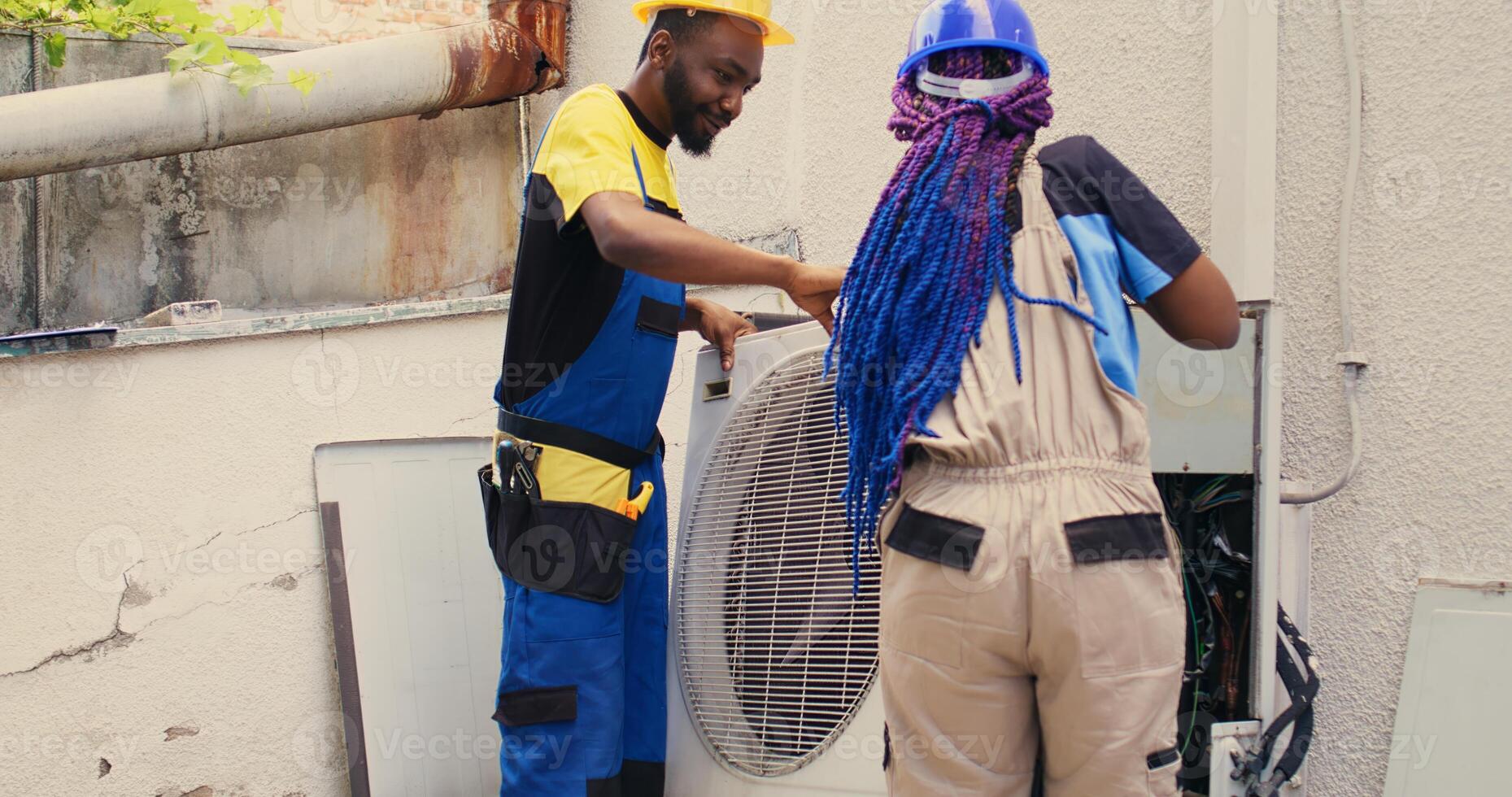 Knowledgeable professionals commissioned by client to work on broken air conditioner, dismantling condenser metal coil panel. Trained engineers opening hvac system to check for faulty components photo