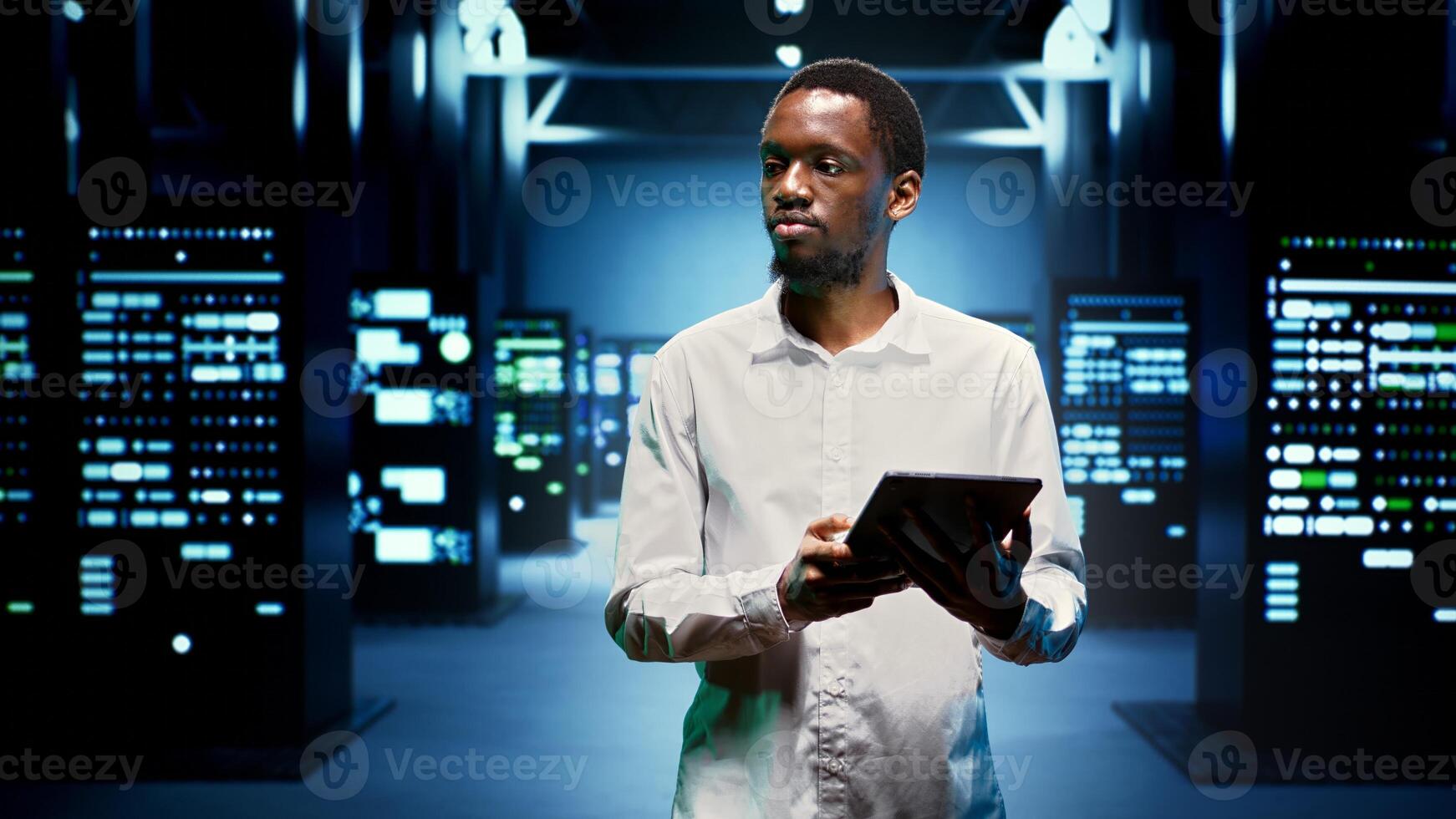 African american technician in high tech facility housing supercomputers, storage devices and networking parts providing vast amounts of computing resources. Specialist doing server racks maintenance photo