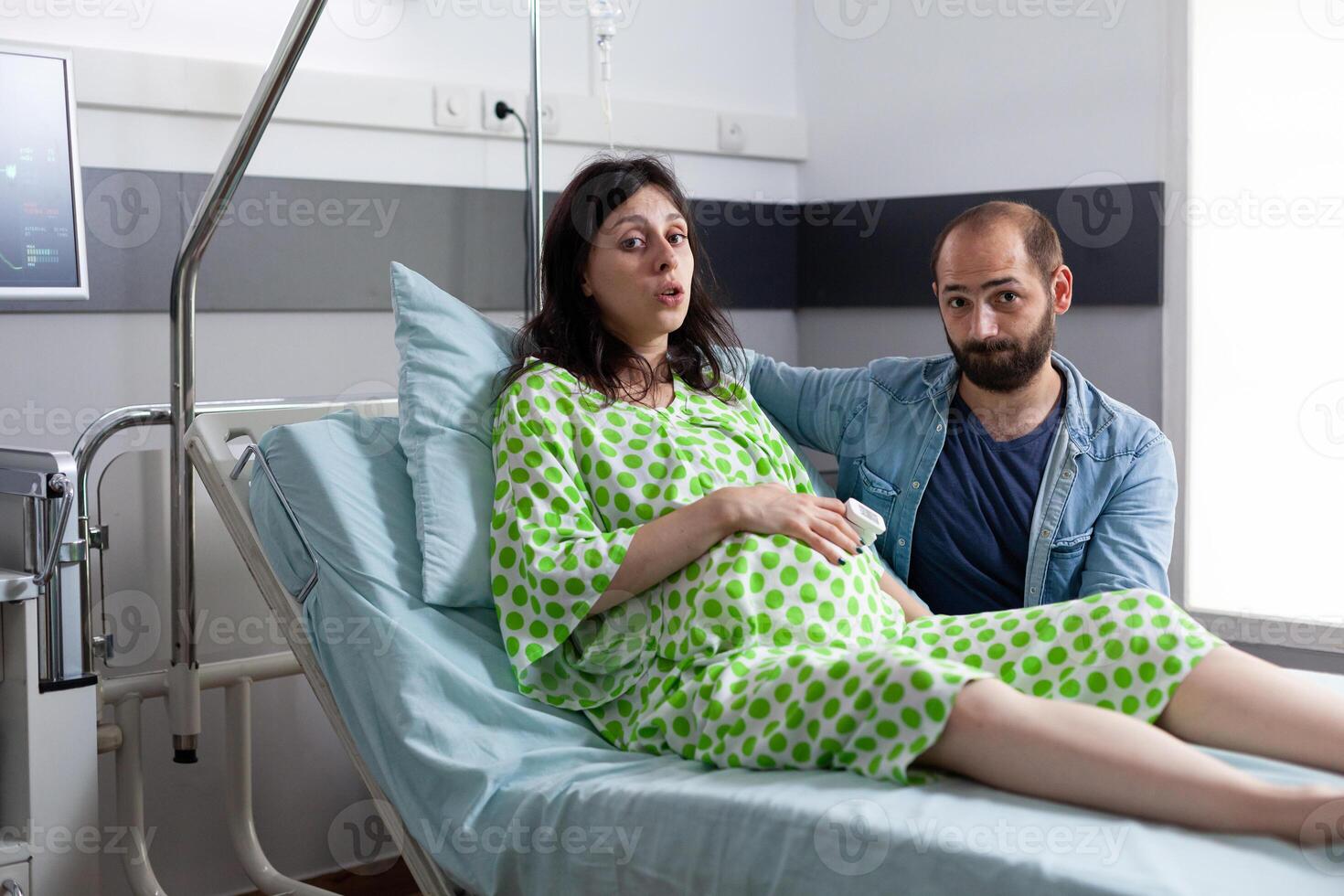 marido Ayudar embarazada mujer con contracciones, haciendo respiración ejercicios en hospital pabellón. paciente con el embarazo acostado en cama esperando para médico a ven y comienzo labor durante chequeo visitar foto