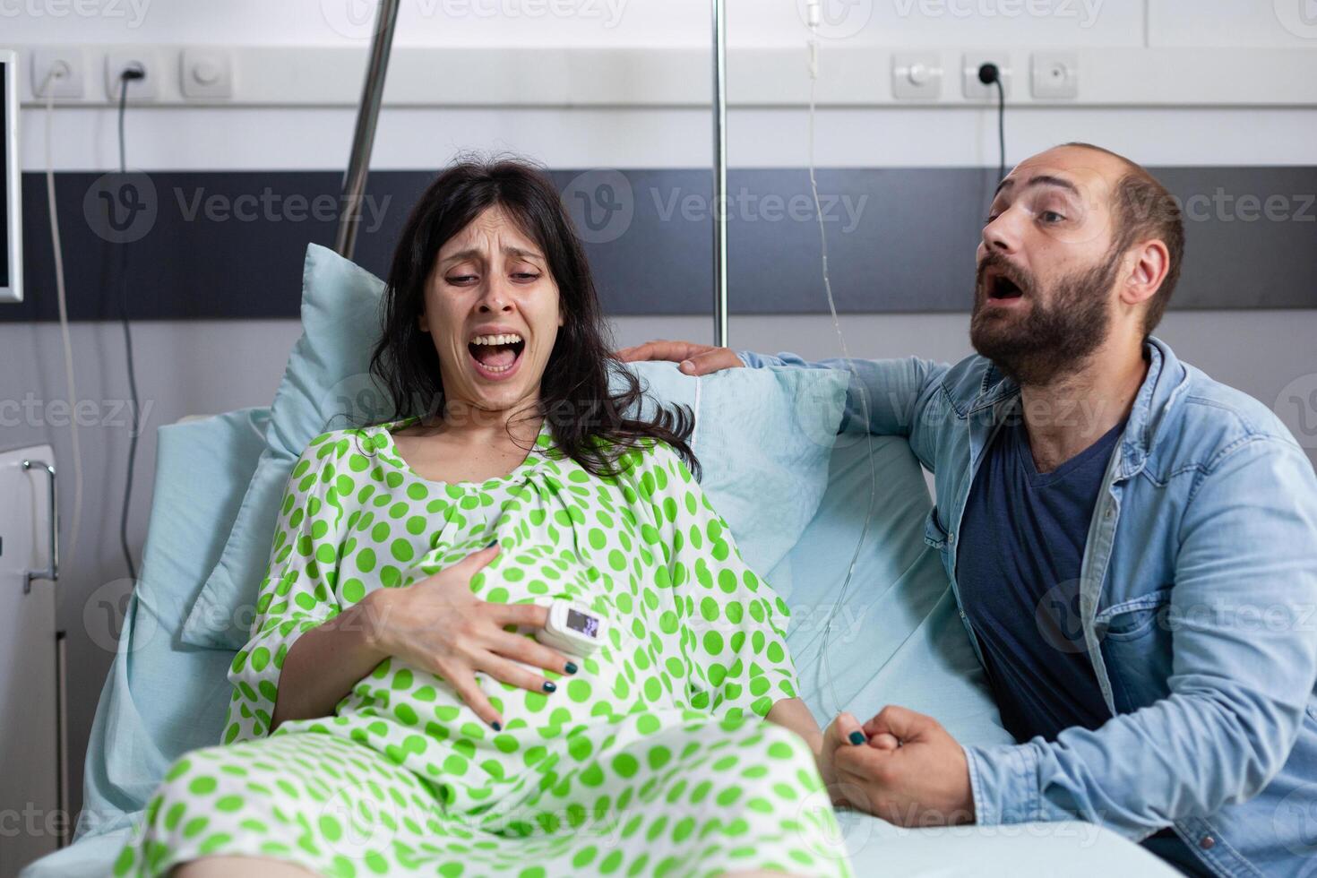 Pregnant woman having painful contractions, getting into labor in hospital ward while nervous husband yelling for doctor and medical assistance. Caucasian young couple preparing for childbirth photo