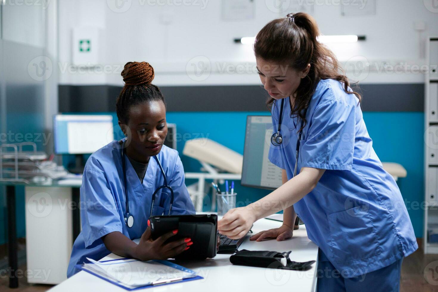 diverso médico cuidado de la salud personal equipo mirando a digital tableta pantalla en moderno profesional clínica oficina. africano americano enfermero comparando datos con compañero de trabajo en hospital lugar de trabajo foto