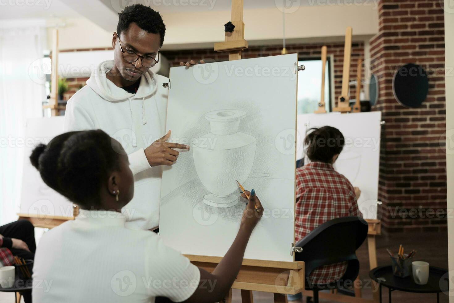 Young African American couple attending group art class together, trying out new things in spare time, teacher helping student during drawing lesson in creative studio. Artistic hobby photo
