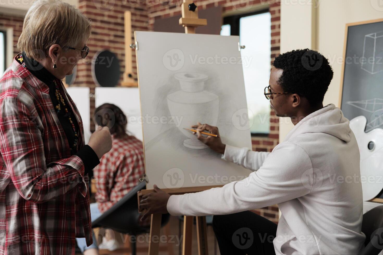 joven africano americano chico instructor enseñando mayor mujer a dibujar durante Arte clase, profesor sentado a caballete demostración maduro estudiante cómo a sostener y utilizar lápiz. tomando arriba dibujo lección en Jubilación foto