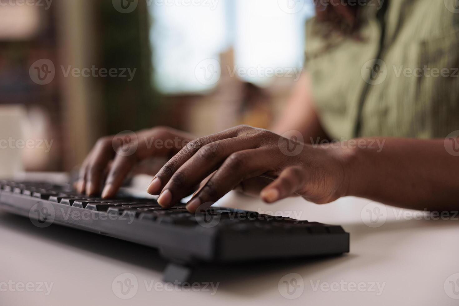 Closeup of african american influencer writing post for social media on computer keyboard while working remote from home living room. Selective focus on woman hands typing blog article. photo