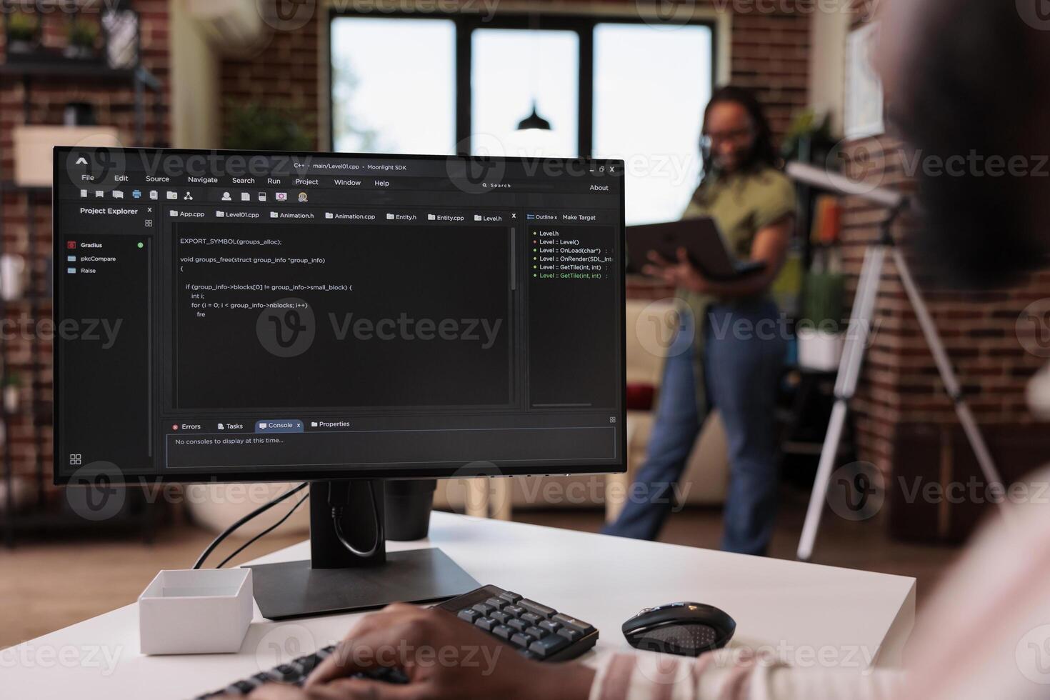 Freelance programmer developing source code on personal computer while girlfriend is using laptop standing in living room. African american couple working remote programming software together. photo