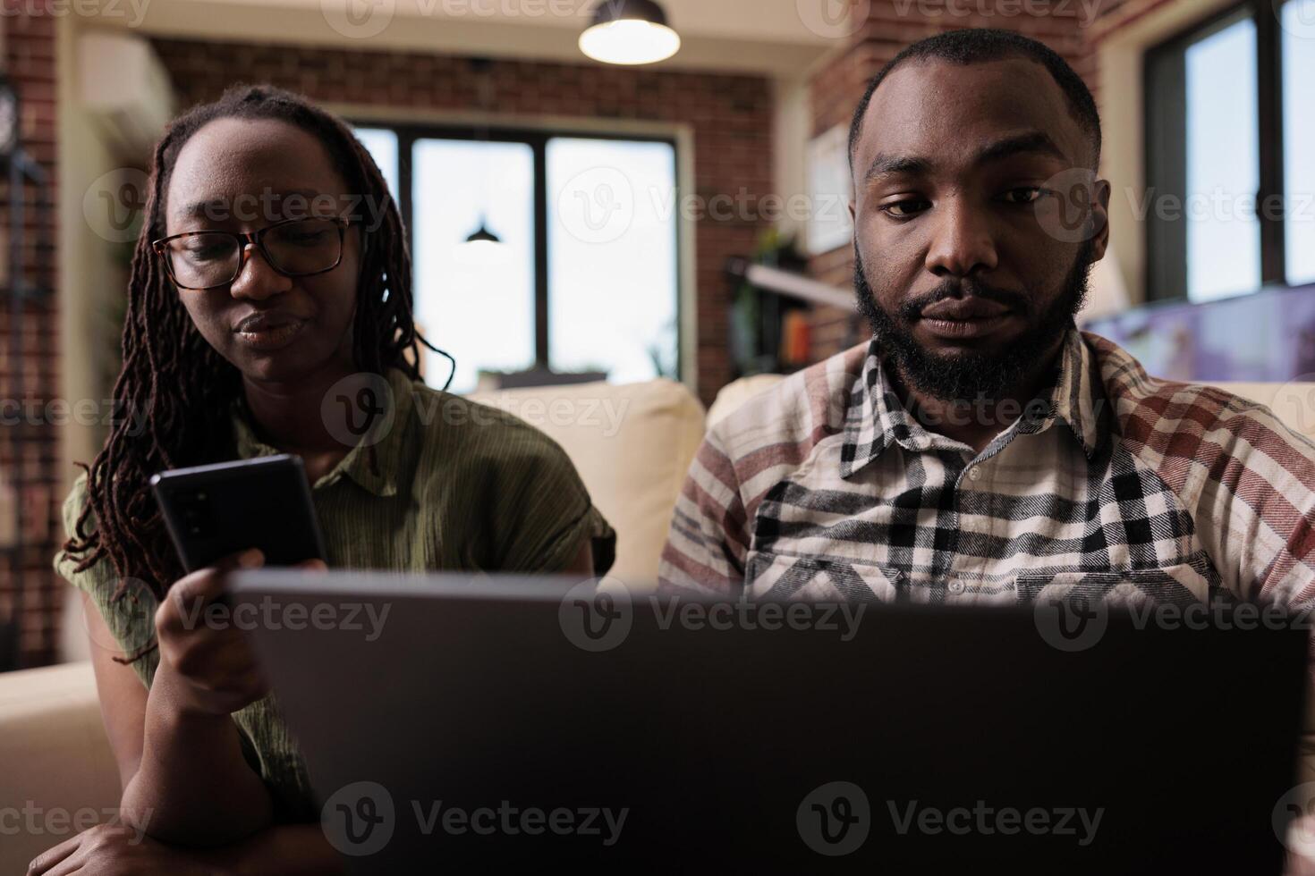 Couple having communication problems not talking to each other and using digital devices ignoring each other. Woman browsing social media on smartphone while man is working on laptop. photo