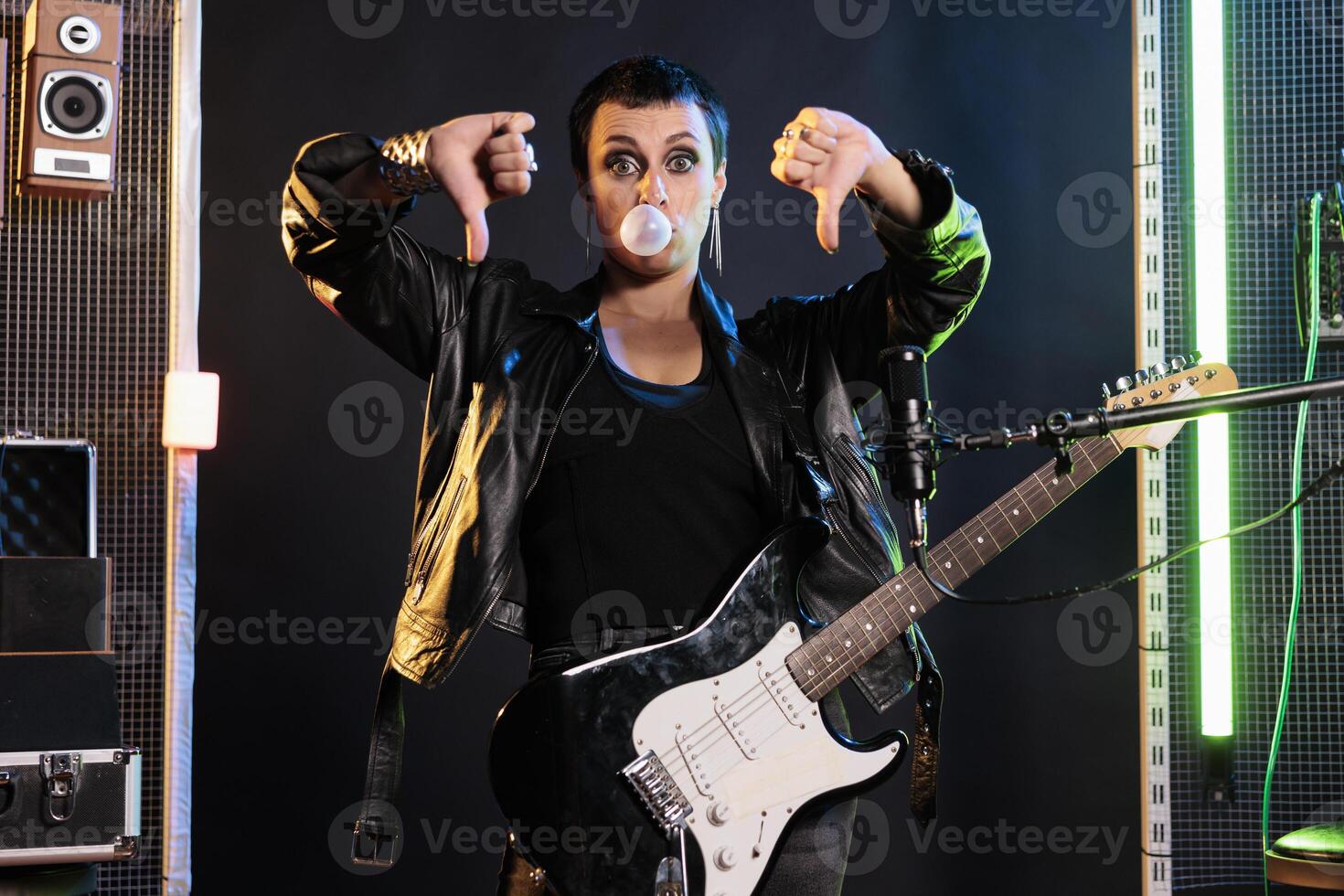 Guitarist showing disapproval sign at camera while performing rock music in  sound studio using electric guitar. Rebel performer doing thumbs down  gesture, playing metal song at solo performance 32624894 Stock Photo at